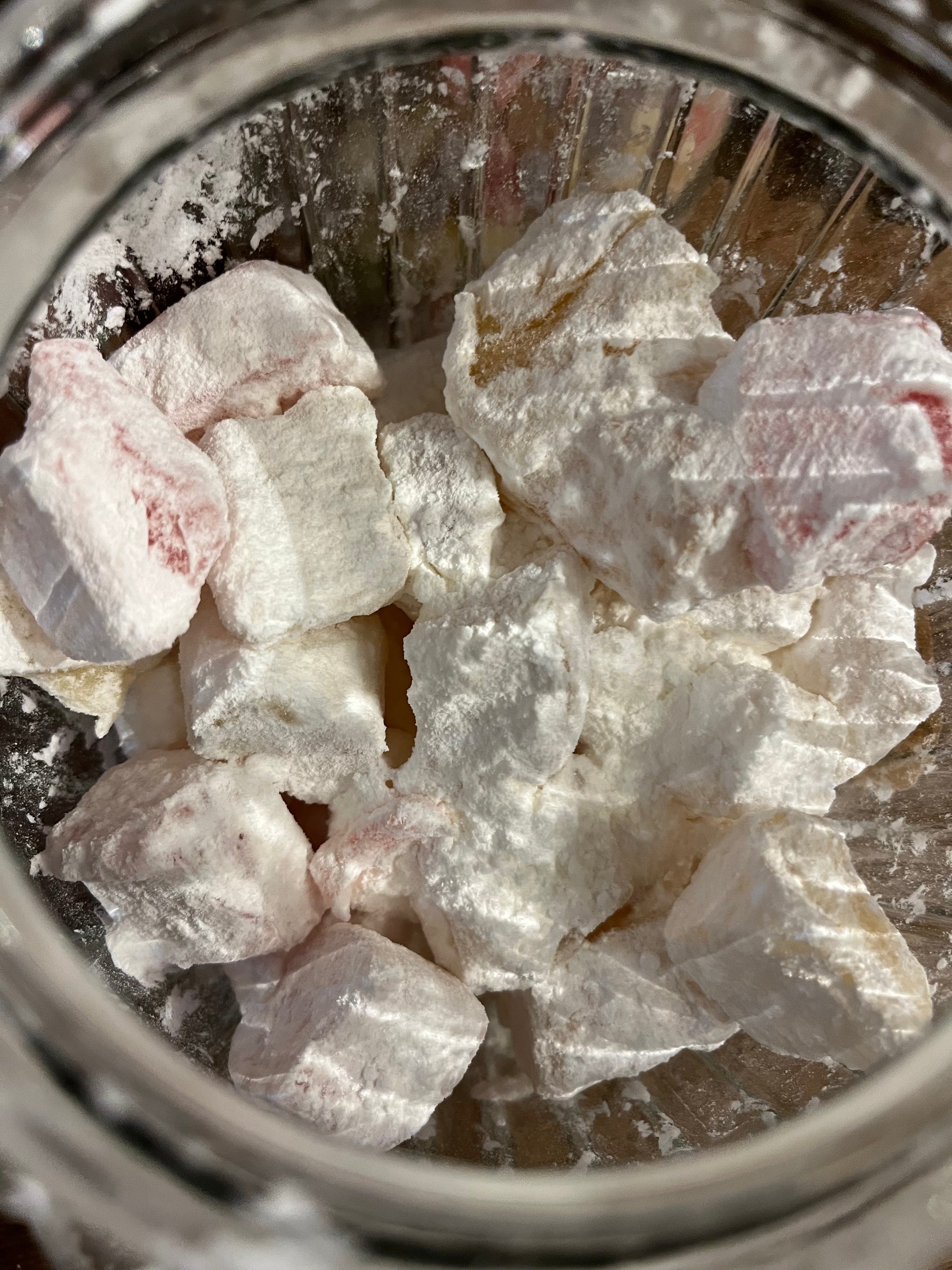 Looking down into an open jar we see pale pink & yellow translucent chunks of turkish delight, dusted heavily with white powdery cornflour