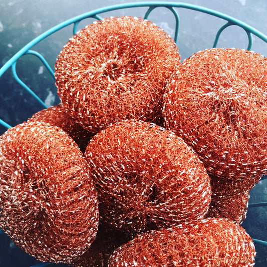 A blue wire basket full of orange copper scourers.